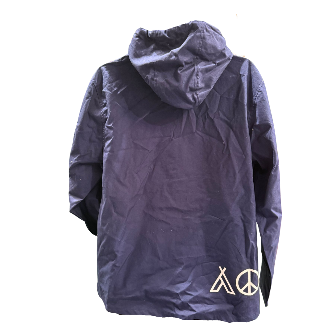 The Camp Bestival Smock Jacket Atlantic by Camp Bestival is a navy blue hooded jacket shown from the back, featuring striking white tent and peace symbol graphics near the bottom hem on one side.