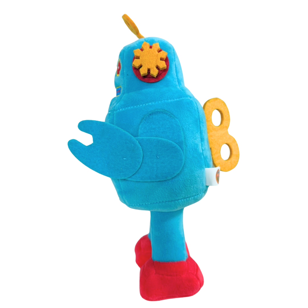 The 2025 Camp Bestival Love-Bot Plush features a blue body, yellow gear eyes, wind-up key back, red feet, and yellow antenna, shown in side profile on a white background.