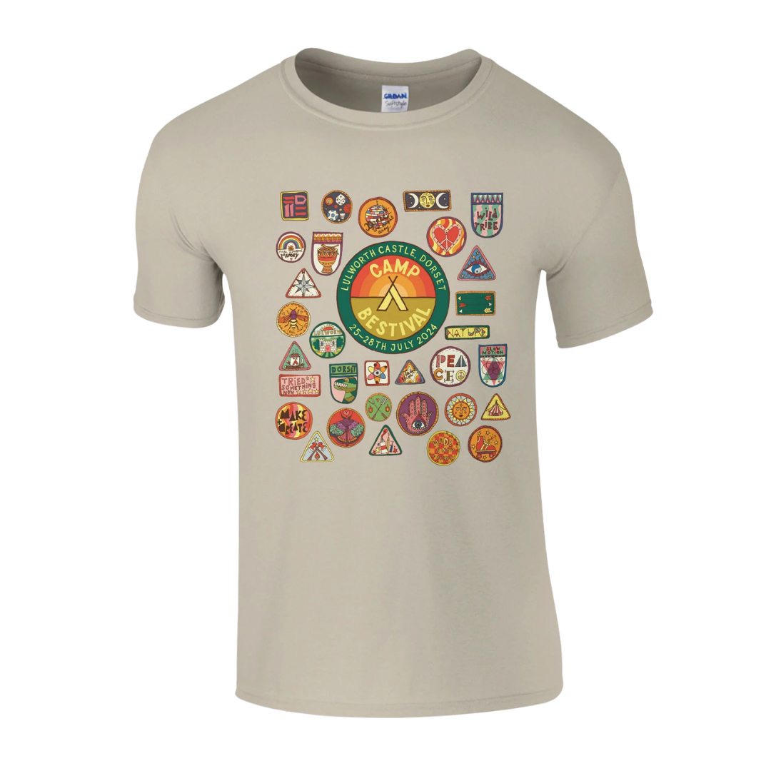 The Camp Bestival 2024 Dorset Event Tee by Camp Bestival is a beige ringspun cotton t-shirt with a large central "Camp Destiny" patch and colorful scout-style badges, offering all-day comfort. Displayed on a plain white background.