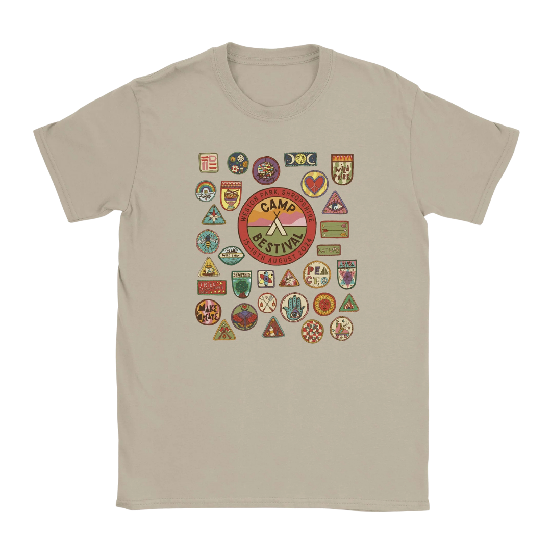 Camp Bestival 2024 Shropshire Event Tee by Camp Bestival: Beige ringspun cotton t-shirt with a large central Camp Festivus badge featuring an axe, tent, and camp-style patches and merit badges in colorful shapes.