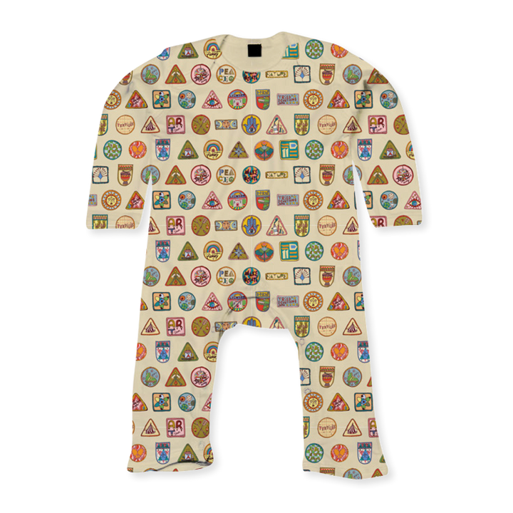 The Camp Bestival Baby Sleep Suit All Over Print by 2025 is a beige suit featuring colorful badges and patches—circles, triangles, and squares—in a grid pattern all over its surface.