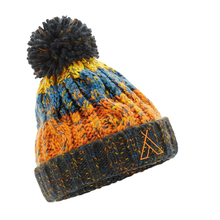 The Camp Bestival Kids Beanie/Bobble Hat by 2025 features a chunky knit in orange, blue, and yellow, a large pom-pom, and a folded dark gray brim with a small logo.