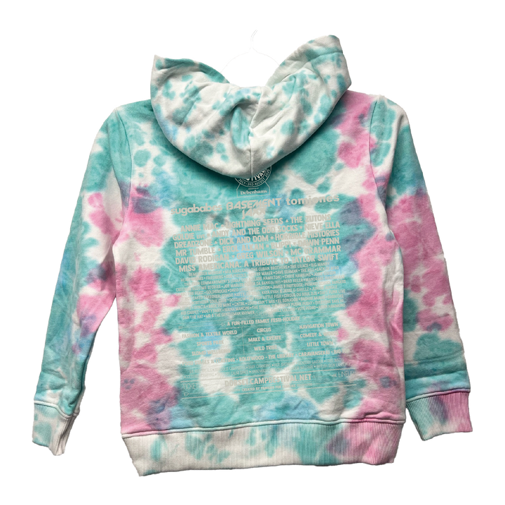 The Camp Bestival 2025 Kids Hoodie by 2025 features a blue and pink tie-dye design with white text in various font sizes printed on the back. Shown on a hanger with the hood up.