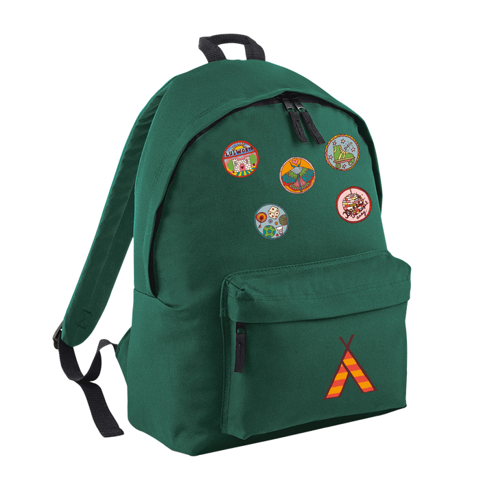 The Camp Bestival Junior Backpack by 2025 features a green design with five colorful scout badges on the front, a small red-and-yellow tent logo on the pocket, and black straps and zippers.