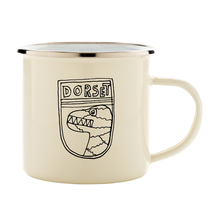 The Camp Bestival Kids Mug White by 2025 is a cream enamel mug with a silver rim, showcasing a line drawing of a dinosaur head inside a shield and DORSET above the illustration.